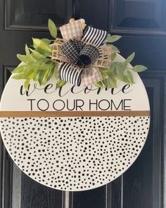 a welcome to our home sign hanging on a door with black and white polka dots