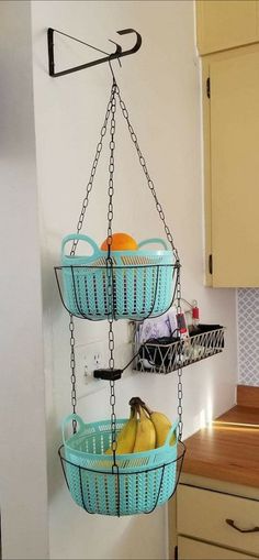 two hanging baskets filled with fruit on top of a kitchen counter