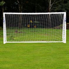 a soccer goal on the grass with trees in the background