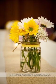 yellow and white flowers are in a mason jar