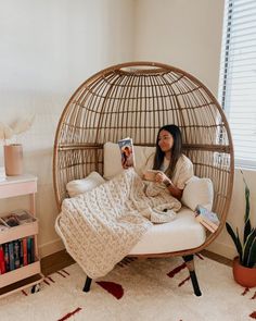 a woman sitting in a hanging chair reading a book