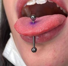 a woman's tongue with two piercings attached to the end of her tongue