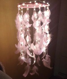 a chandelier with lights and feathers hanging from it's sides in a dark room