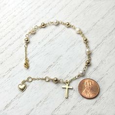 This Cross Rosary Bracelet is a beautifully handcrafted piece with freshwater pearls and gold-filled accents. Adorned with a cross and heart charm, it is the perfect addition to any Christian's jewelry collection. * Choose your size. Adjustable adult wrist. * Freshwater pearl 4~5mm.* Cross and heart charms: 11mm.* Gold plated over brass.* Lead and Cadmium Free & Nickel Safe. Hypoallergenic.* Handmade in New Jersey.* Due to the nature of freshwater pearls, there will be variations in color, size, and patterns. However, we handpick pearls where shape, color, and size are as similar as possible.✔️ Please note that while our pictures are as true to life as possible, colors may appear differently on your screen.✔️ All our products are packaged with care and tracking numbers. Adjustable Gold Rosary Bracelet With Pearl Charm, Gold-plated Rosary Bracelet For Gift, Hand-strung Gold Rosary Bracelet, Elegant Adjustable Gold-plated Rosary Bracelet, Cross Rosary, Silver Cross-shaped Rosary Bracelet With 8mm Beads, Rosary Bracelet, Christian Jewelry, Gold Cross