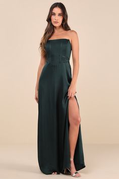 a woman in a long green dress posing for the camera with her legs slited