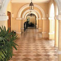 an arched hallway with tiled flooring and potted plants in the center on either side