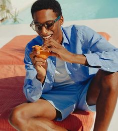 a man sitting on a towel eating food