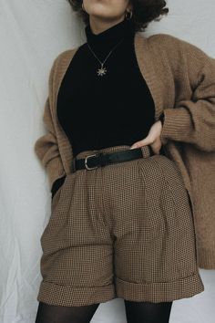 a woman in black shirt and plaid shorts posing for the camera with her hands on her hips