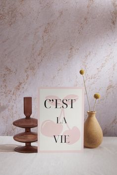 a card that says c'est la vie next to a vase with flowers