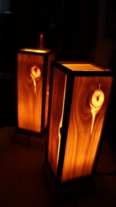 two wooden lamps sitting on top of a table next to each other in the dark