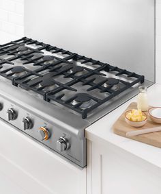 a stove top with two burners and a cutting board on the counter next to it