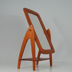 a wooden chair with a mirror on it's back end and legs in the shape of a triangle