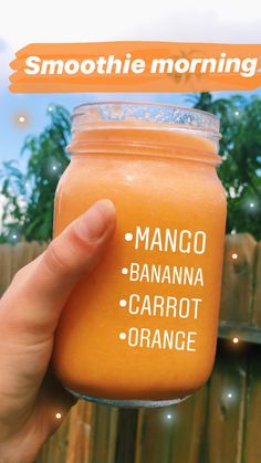 a hand holding up a jar of orange smoothie with the words mango, banana, carrot and orange on it