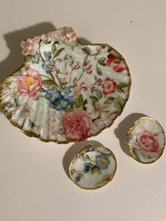 three pieces of porcelain sitting on top of a white table next to two plates and one bowl