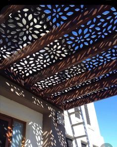 an outdoor pergolated roof with the sun shining through it and shadows on the ground