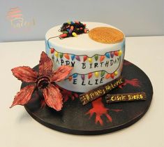 a birthday cake decorated with candy and candies on a black plate next to a flower