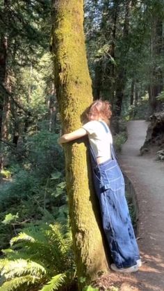 a person leaning against a tree in the woods