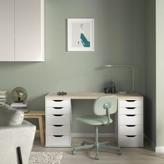 a white desk with drawers and a chair in a room that has light green walls