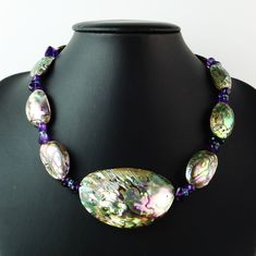 Discover the captivating beauty of this Paua Shell choker necklace, also known as Abalone, featuring stunning accents of tumbled Purple Amethyst and faceted Teal Apatite. The Paua Shell's mesmerizing, multi-colored hues—ranging from blue, teal, and green to pink, gray, purple, and black—create a swirling design that is unique to each shell. The center focal piece measures an impressive 57x35mm, while the surrounding shell beads are 27x18mm, making this 17.25-inch necklace a true statement piece. British Crown Jewels, Vintage Jewelry Ideas, Shell Choker, Artisan Bracelets, Vintage Beads Necklace, Paua Shell, Unusual Jewelry, Blue Teal, Short Necklace