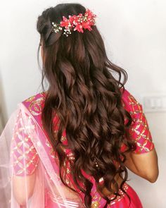 a woman with long dark hair wearing a pink sari and a flower headpiece