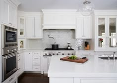 a kitchen with white cabinets and an island in the middle is seen from across the room