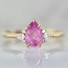 a pink sapphire and diamond ring on a white surface