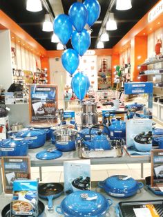 a table with blue plates and balloons on it in a room filled with other items