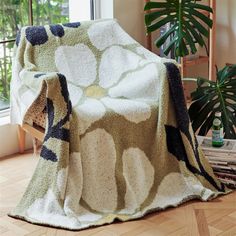 a blanket that is on the floor next to a chair and potted plant in front of a window