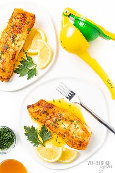 two white plates topped with fish next to lemon wedges and parsley garnish