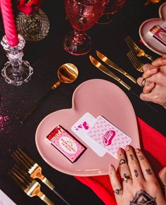 a table set for valentine's day with cards, candles and napkins in the shape of a heart