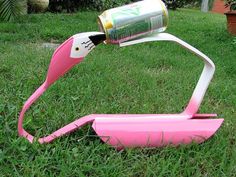 a pink lawn mower sitting in the grass with a can on it's back