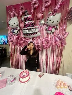 a woman standing in front of a table with pink and white balloons on the wall