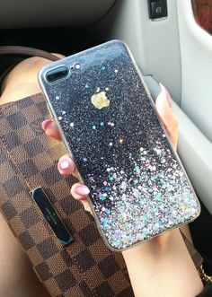 a woman holding an iphone in her hand while sitting in the backseat of a car