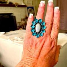 This Is A Beautiful Authentic Hand Made Larimar Blue Topaz And Sterling Silver Ring. Size 8 1/2. It Features A Beautiful Authentic Blue Larimar Center Stone That Is Surrounded By Beautiful Authentic Blue Topaz Stones. It Is Fashioned In A Lovely Flower Shaped Sterling Silver Setting. This Is A Beautiful Large Statement Ring. It Is Heirloom Quality. Blue Multi-stone Moonstone Anniversary Ring, Blue Multi-stone Moonstone Ring Gift, Blue Multi-stone Moonstone Ring For Anniversary, Gift Blue Multi-stone Moonstone Ring, Anniversary Blue Moonstone Ring With Multi-stones, Blue Moonstone Ring With Gemstone Accents, Blue Oval Moonstone Ring With Gemstone Accents, Blue Topaz Stone, Flower Shape