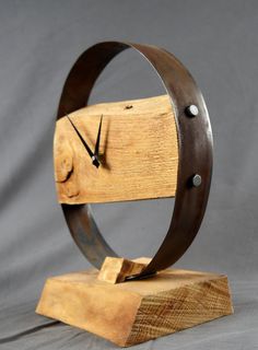 a clock made out of wood on top of a piece of wood with a metal ring around it