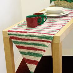 a table topped with a red and green striped runner next to a potted plant