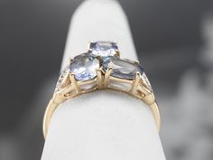 This tanzanite band is feminine and elegant! The purplish-blue of the stones pairs perfectly with the gold band, while the white sapphires add a pop of light that enhances the sparkle of the tanzanites. This ring would stack well with other bands! Metal: 10K Yellow and White Gold Gem: 3 Tanzanites totaling 1.95 Carats Gem Measurements: 5 x 7 mm, Oval Accents: 8 White Sapphires totaling .07 Carats Ring Size: 8.25 Marks: "CR 375" Stamped on the inside band Fine Jewelry Tanzanite Three Stone Sapphire Ring, Tanzanite Rings With Diamond Accents For Promise, Yellow Gold Tanzanite Sapphire Ring With Accent Stones, Yellow Gold Sapphire Ring With Tanzanite And Accent Stones, Tanzanite Rings With Gemstone Accents For Anniversary, Wedding Sapphire Ring With Tanzanite Gemstone Accents, Tanzanite Multi-stone Fine Jewelry Ring, Tanzanite Three-stone Ring For Anniversary, Tanzanite Three Stone Rings For Anniversary