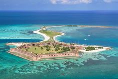 an island in the middle of the ocean surrounded by blue water and green land with buildings on it