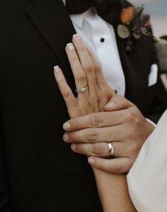 the bride and groom are holding each other's hands with wedding rings on their fingers