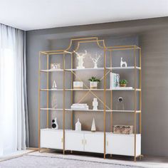 a white and gold bookcase in a living room with grey walls, rugs and curtains