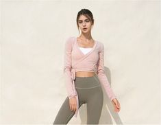 a woman in grey leggings and a pink crop top posing for a photo