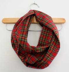 a red and green plaid scarf hanging on a coat rack in front of a white wall