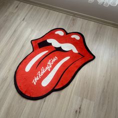 a rug with the rolling stones logo on it is laying on a wooden floor in front of a white wall