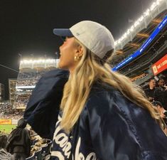 a woman in a baseball cap and jacket at a game