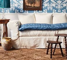 a living room with blue and white wallpaper, a couch, table and chair