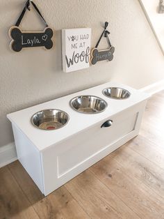 a white dog bowl with two bowls hanging on the wall