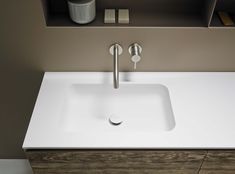 a white sink sitting under a bathroom mirror next to a wooden shelf with soap dispensers on it