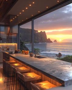 a kitchen with an island counter and bar stools next to the ocean at sunset