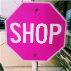 a pink stop sign sitting on the side of a road