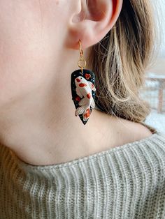 a close up of a person wearing some kind of earring with fish on it